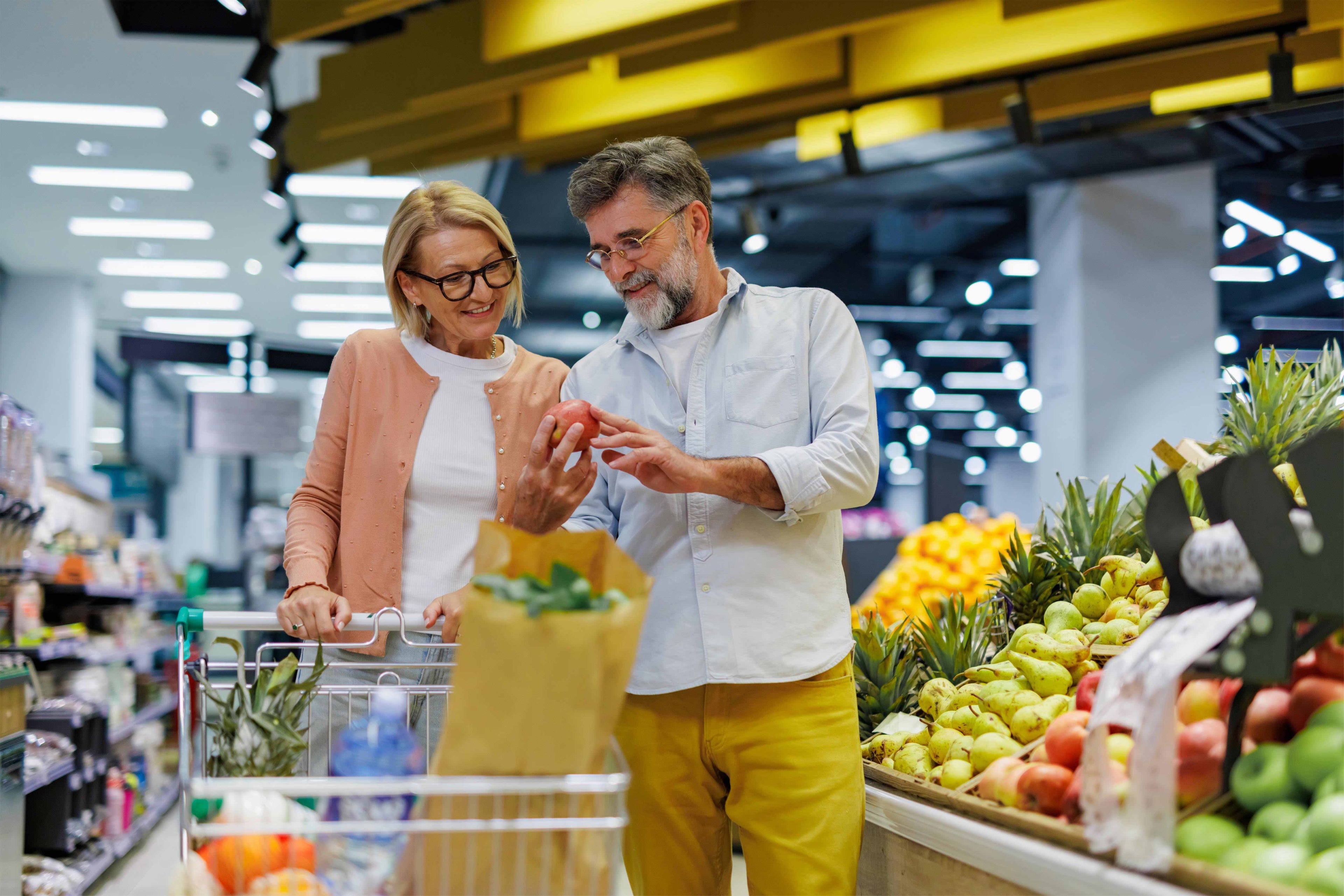 Mature couple shopping for apples in grocery store
